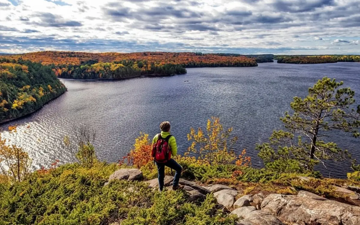 Hiker overlooking a lake from a rocky cliff in Algonquin Park during fall