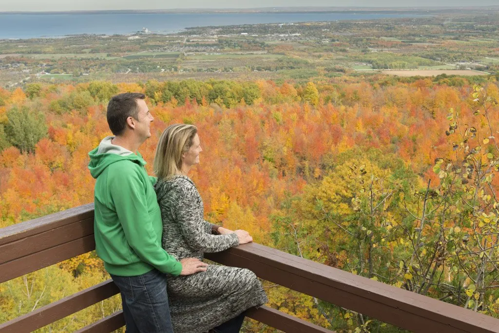 Couple admiring panoramic fall foliage from a lookout point at Blue Mountain.