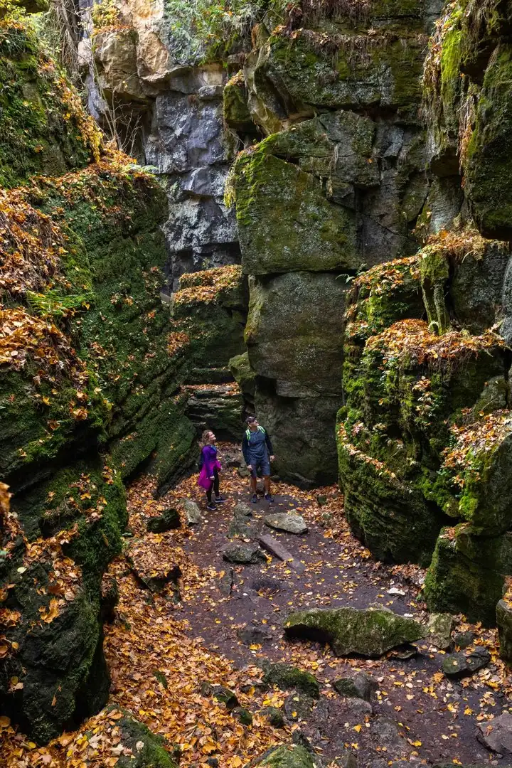 Visitors exploring moss-covered rock formations at Scenic Caves during the fall season.