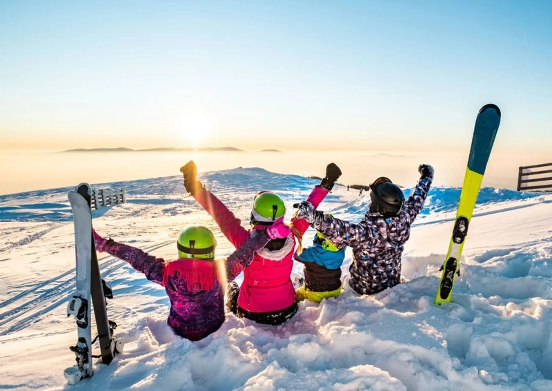 Happy family of skiers celebrating at sunrise with Blue Mountain slopes in background