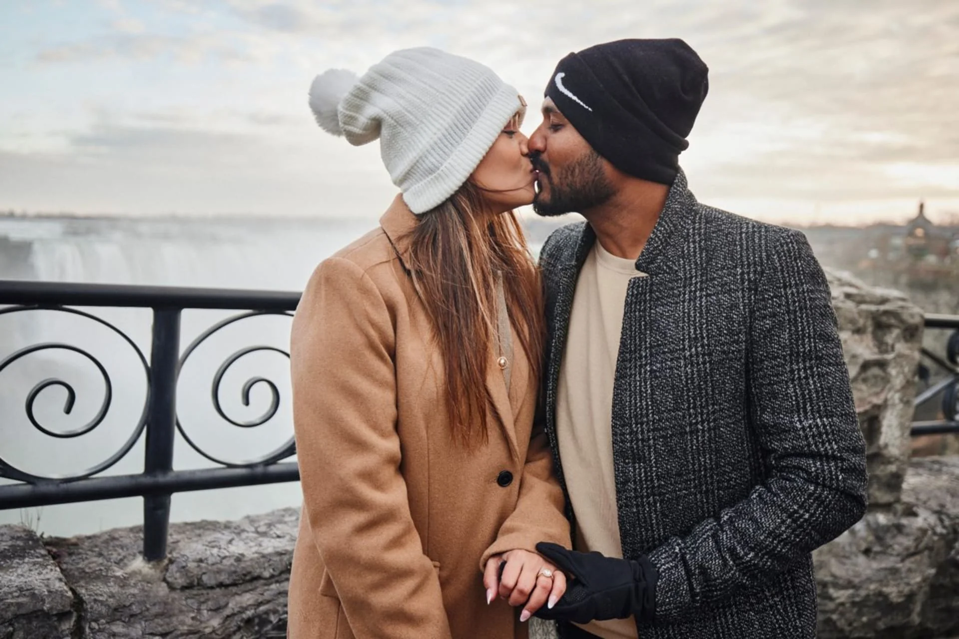 Romantic couple kissing at Niagara Falls with winter lights and festive illuminations