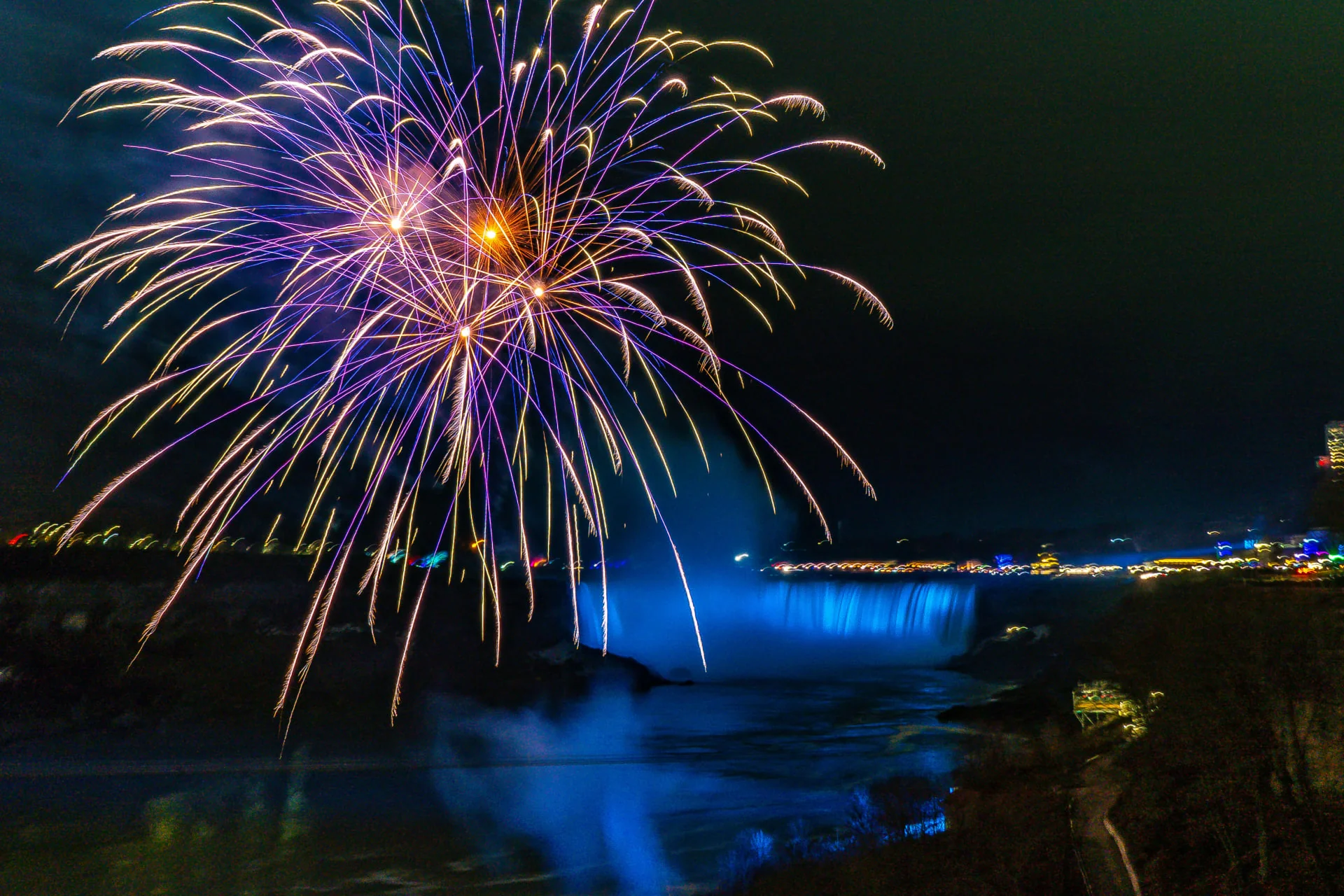 Spectacular winter fireworks display over Niagara Falls illuminating the night sky