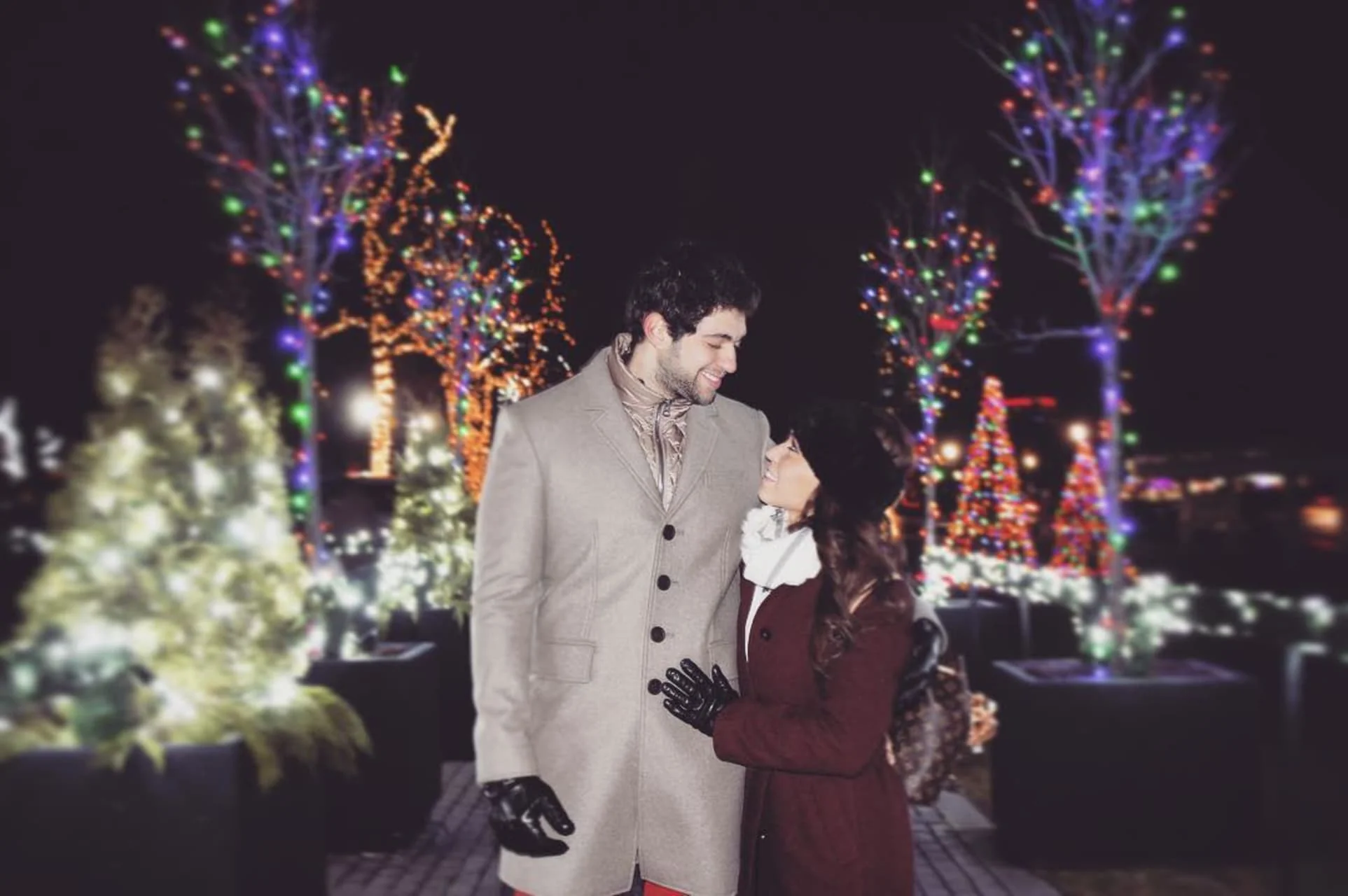 Romantic couple embracing during Niagara Winter Festival of Lights with colorful illuminations in background