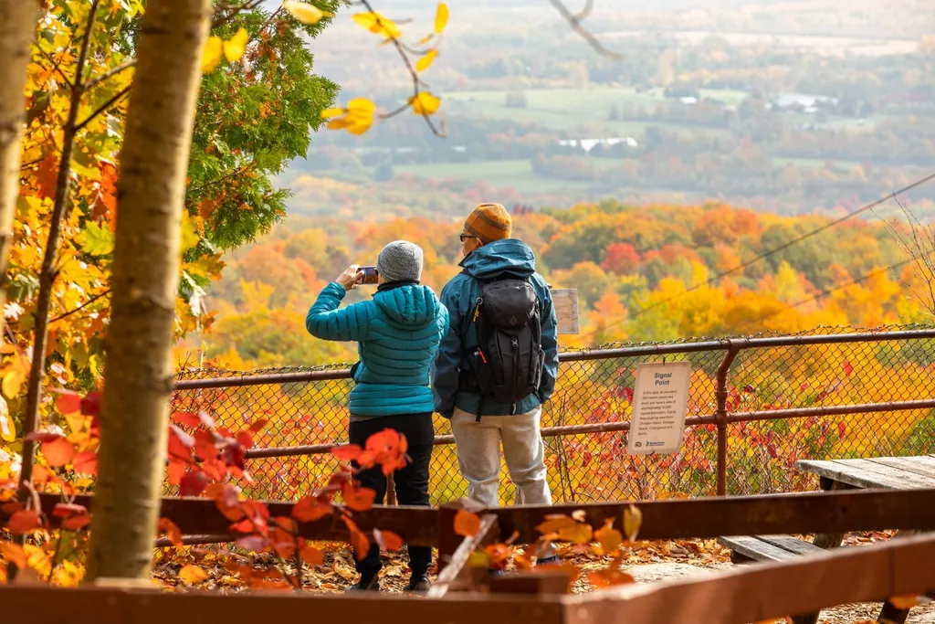 Visitors capturing photos at Signal Point lookout with panoramic fall foliage views.