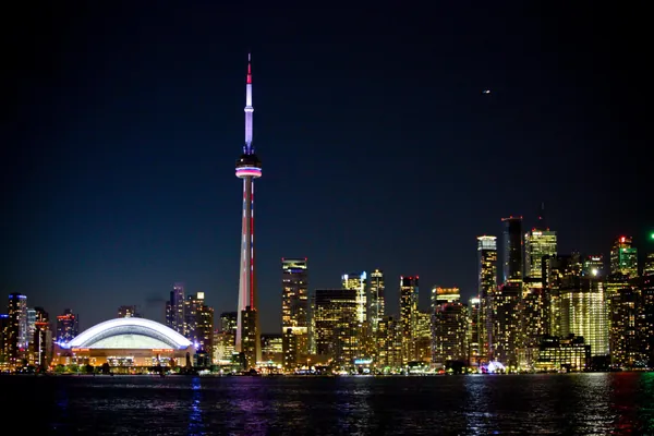 Stunning nighttime view of Toronto's illuminated skyline reflecting over Lake Ontario, showcasing the beautiful cityscape